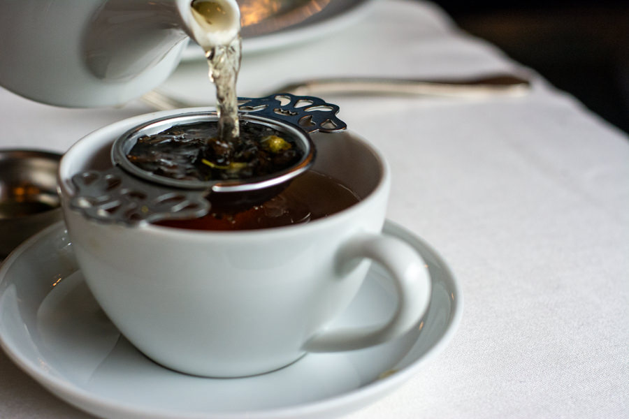 Pouring loose leaf tea into a strainer and cup.
