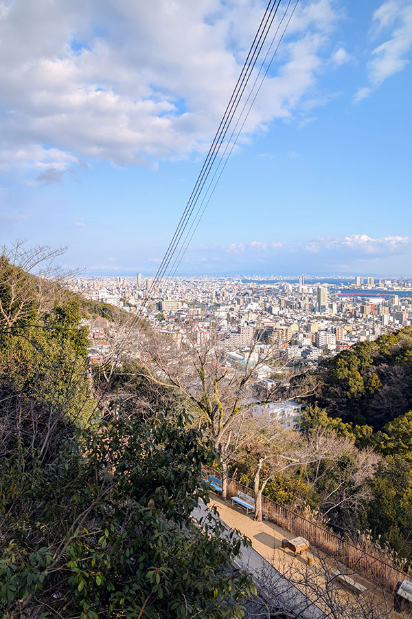 Scenic overlook on the Nunobiki trail above Kobe, Japan, with benches and panoramic views of the city and Osaka Bay below