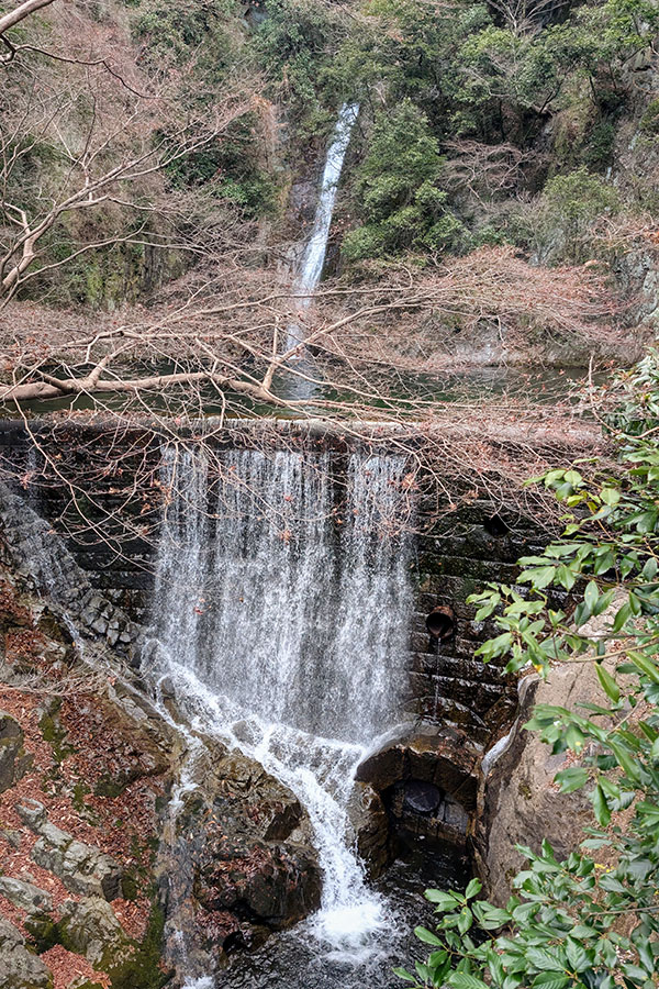 Men-taki Waterfall in Kobe, Japan, cascading over stone terraces in a forested gorge near the Nunobiki hiking trail