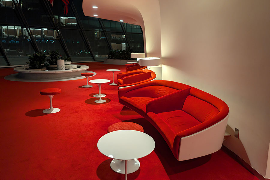 Red curved modular sofas and white tulip tables in the TWA Hotel Ambassador's Club