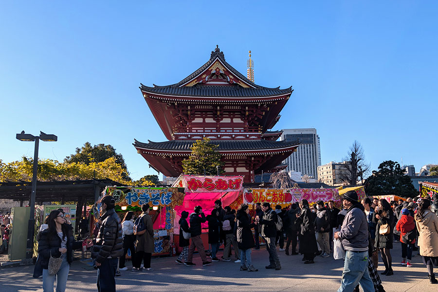 “Crowds gathering at Senso-ji Temple in Tokyo for a winter street festival with food stalls and bright signage