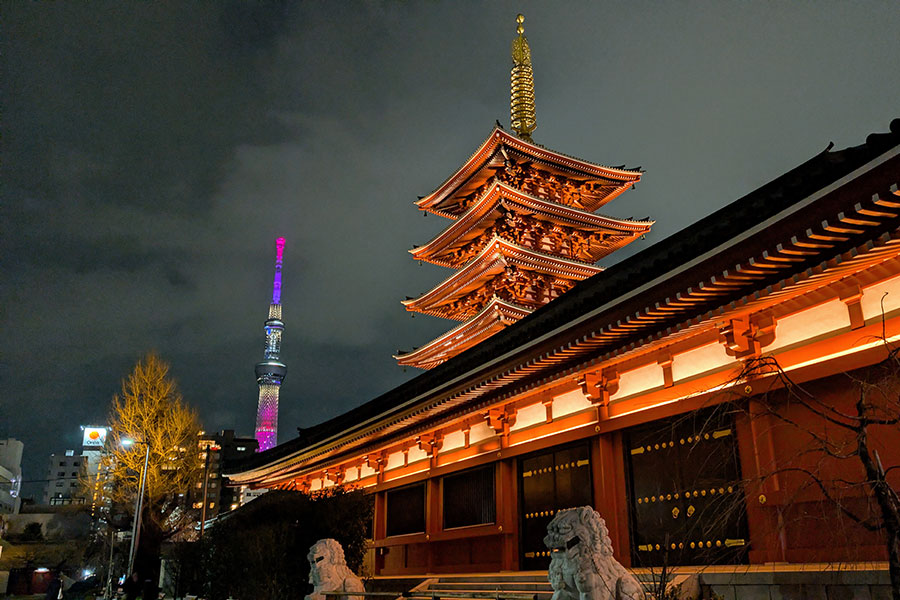 Senso-ji Temple pagoda lit up at night with Tokyo Skytree glowing in the background during a winter evening