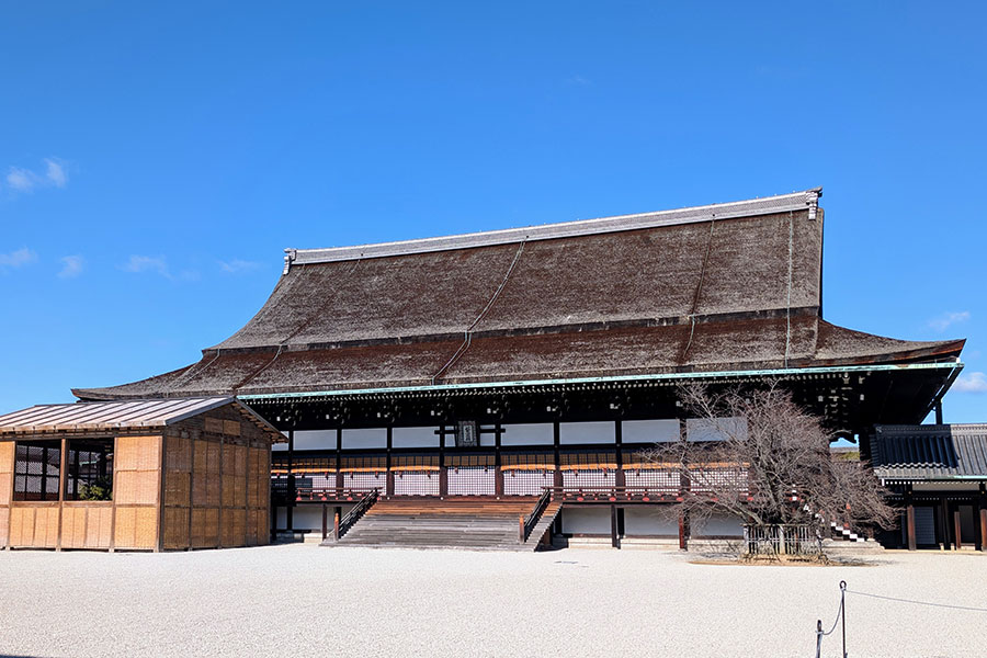 The Shishinden, the Hall for State Ceremonies at the Kyoto Imperial Palace, viewed from across its vast white gravel courtyard under a clear blue sky.