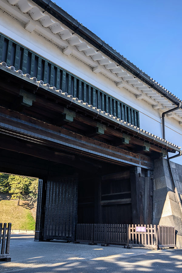 A low-angle close-up of the massive dark wooden beams and structure of the inner gate at Sakuradamon Gate, Tokyo Imperial Palace.