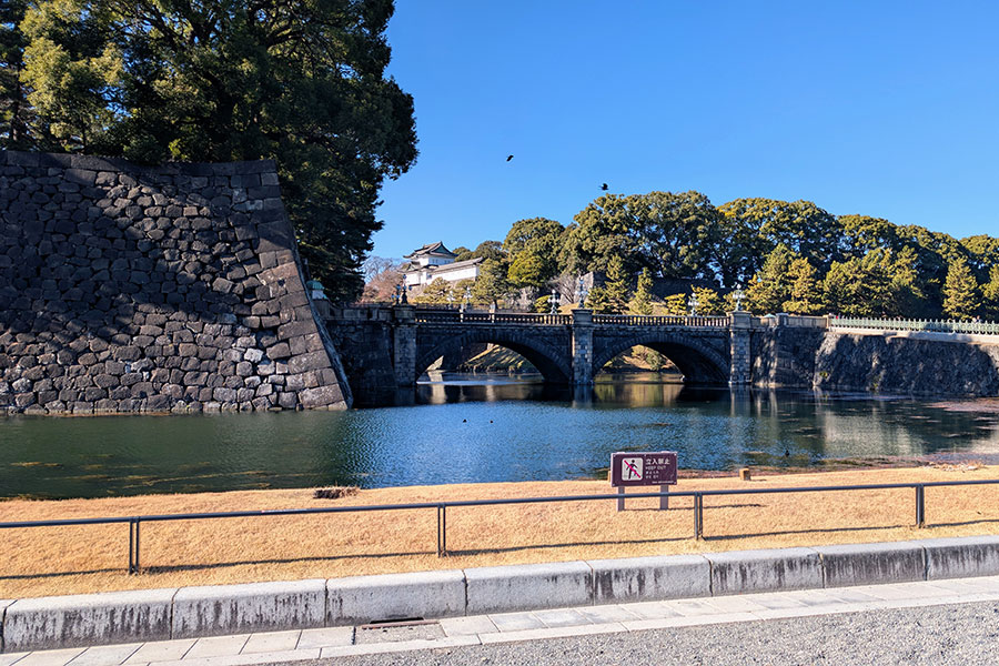 The iconic Nijubashi Bridge, or Seimon Ishibashi, spanning the moat leading to the main entrance of the Tokyo Imperial Palace on a clear day.