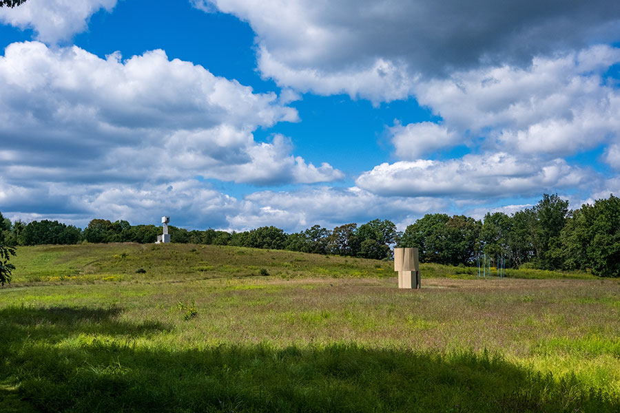 Sweeping view of the large-scale contemporary sculptures of architecture dotting the rolling fields of Art Omi sculpture park in Ghent, NY, that offer some of the best Hudson Valley art.