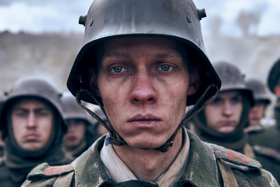 A mud-covered soldier in a trench scene from the German film All Quiet on the Western Front, a must-watch German movie for streaming.