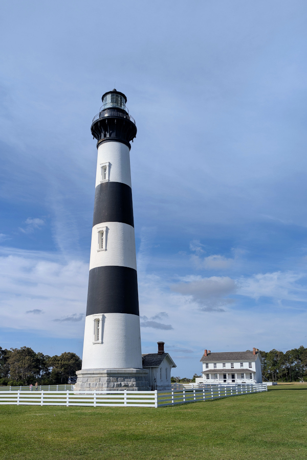 Bodie Island Lighthouse in the Outer Banks of North Carolina, showing the black-and-white striped tower with the historic keepers’ houses on the lawn below.