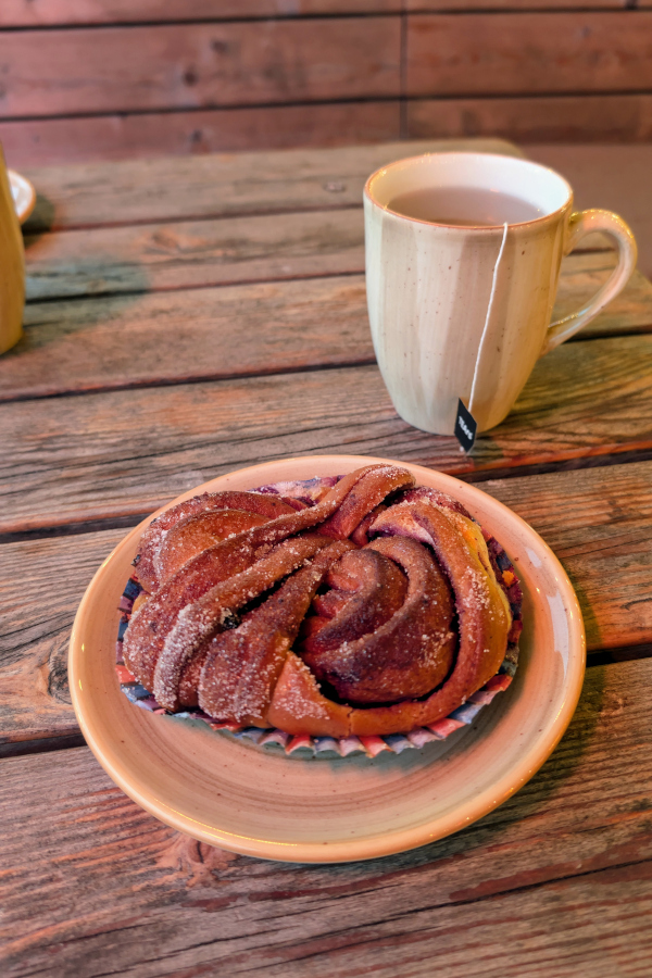 Swedish blueberry bun (blåbärsbulle) filled with blueberries, served on a plate during a traditional fika.